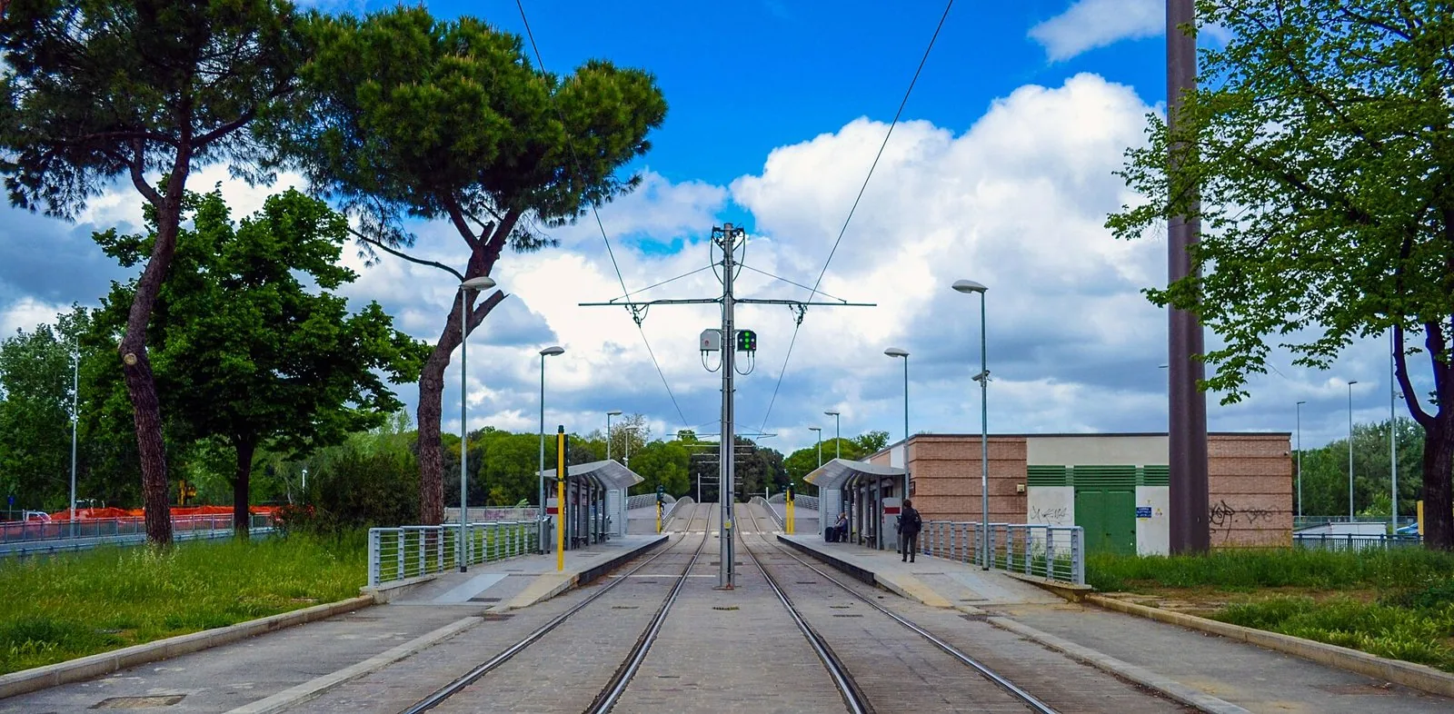 Binari e banchine di una fermata della tramvia di Firenze tra pini e alberi